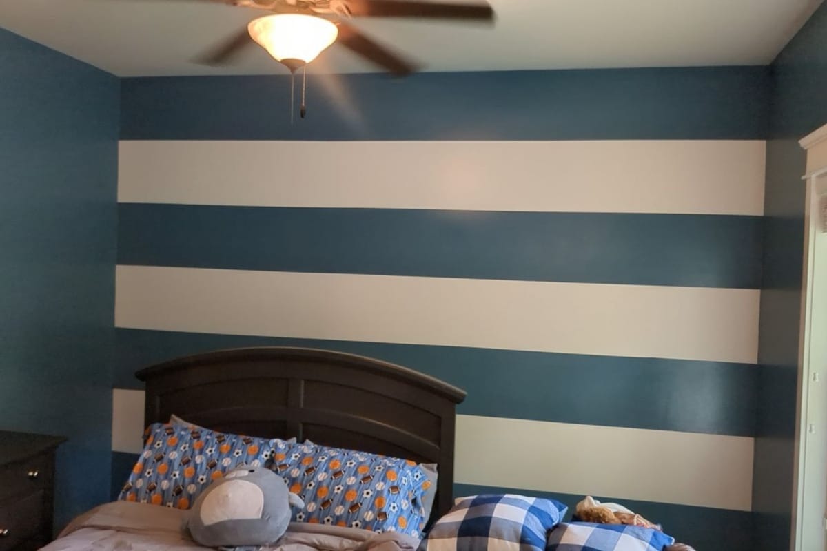 Bedroom with a hand-painted wide horizontal stripe accent wall in slate blue and white