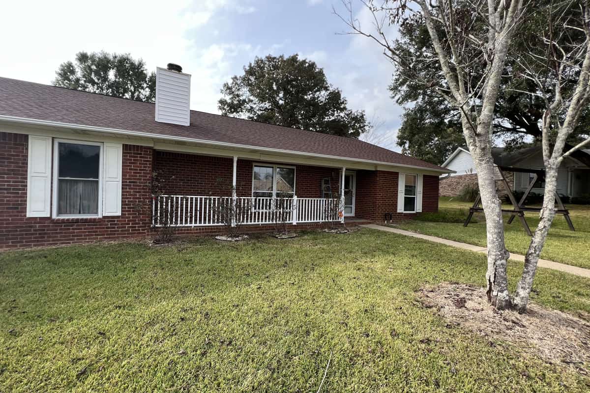 Brick ranch house with freshly painted white trim, shutters and porch rail