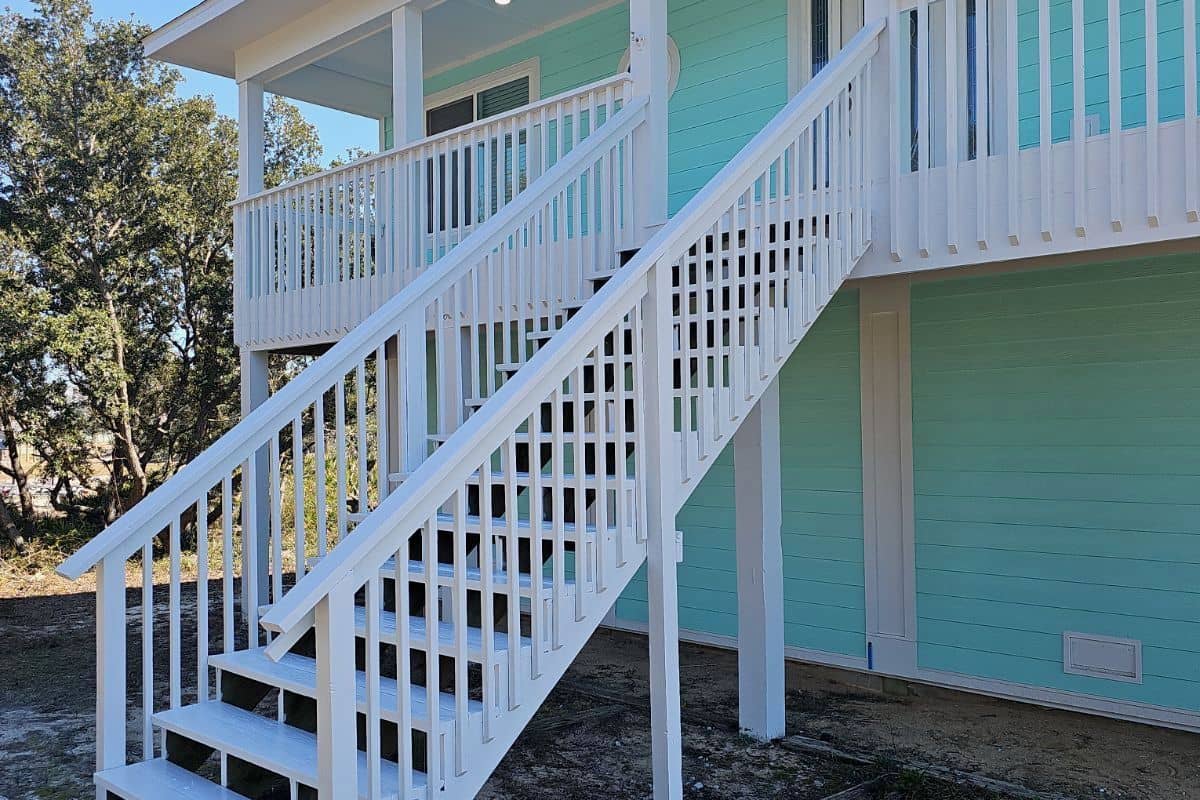 Raised home painted mint green and white with a new exterior staircase