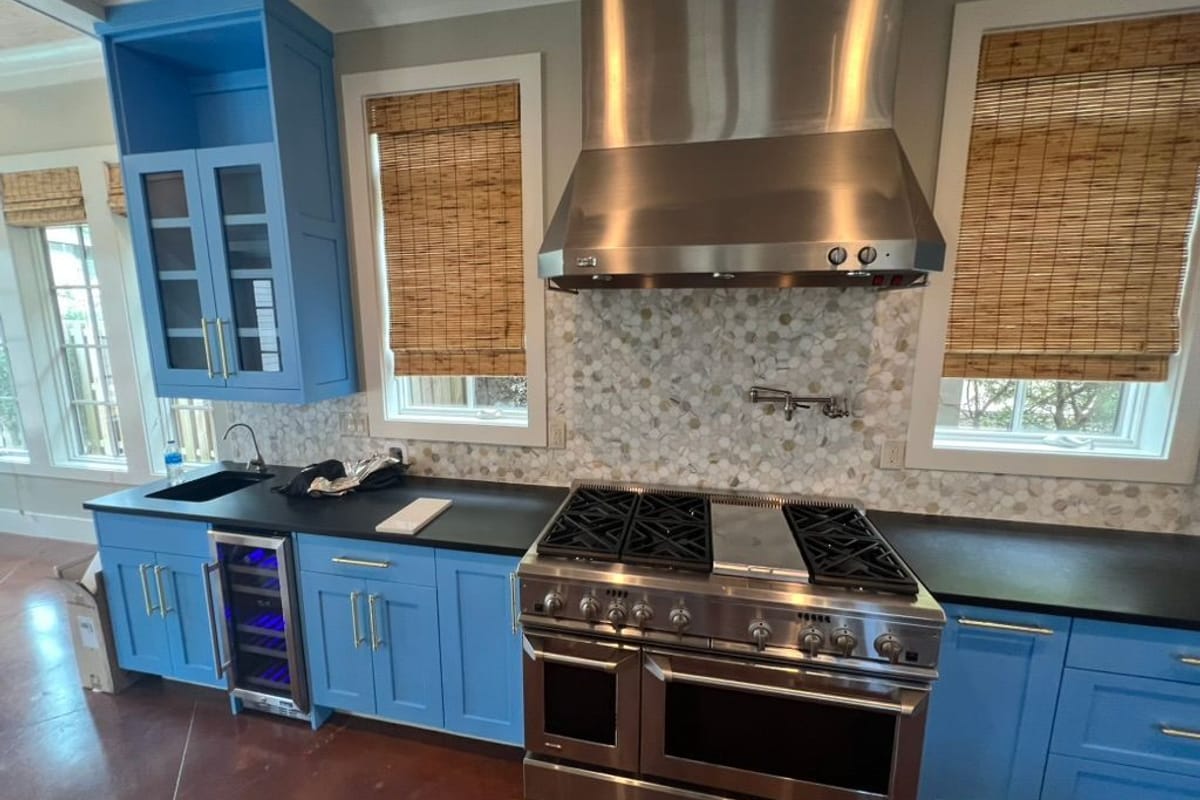 Kitchen cabinets painted blue around a professional range and stainless hood