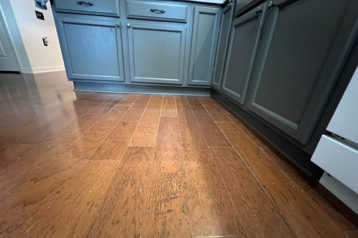 Close view of grey-green painted lower cabinets beside a dishwasher