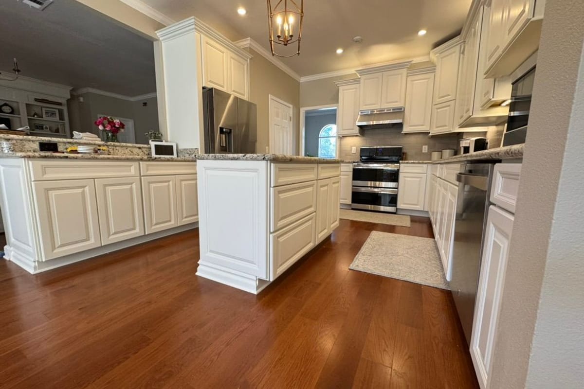 Kitchen with white sprayed cabinets, a white island and stainless appliances