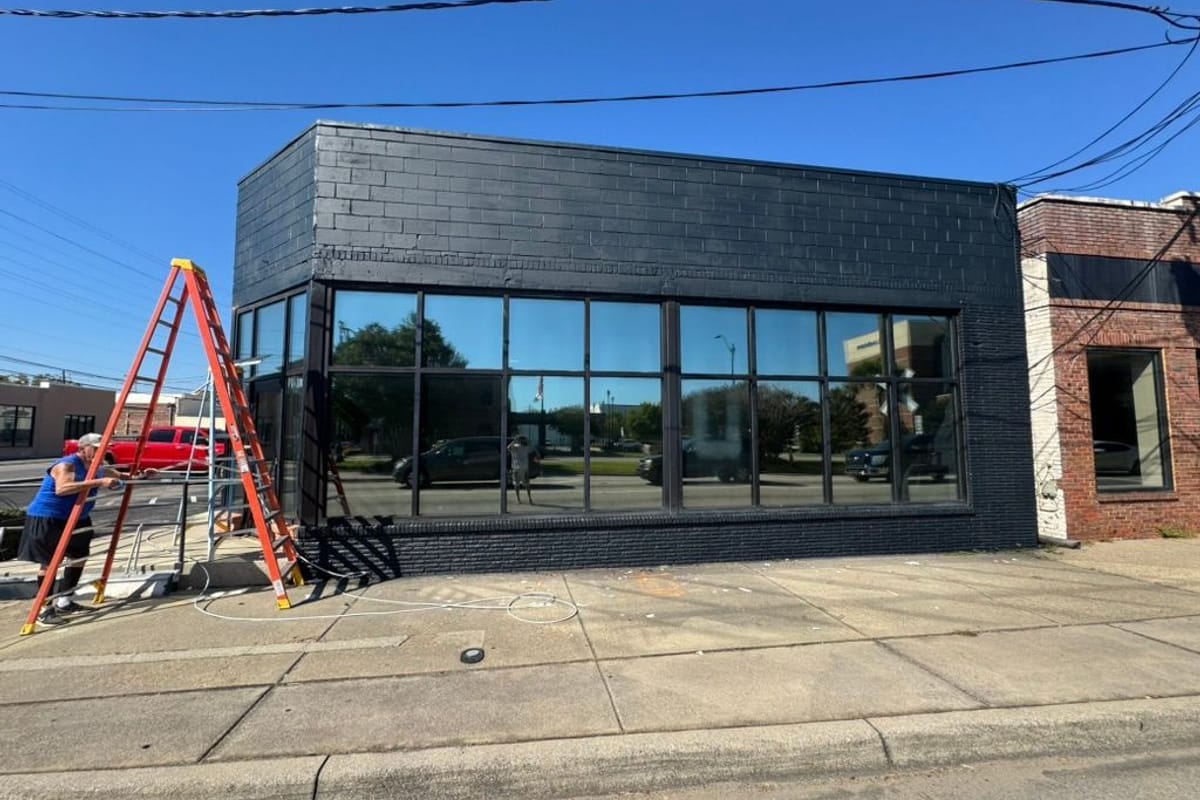 Commercial storefront painted black with a ladder set against the front