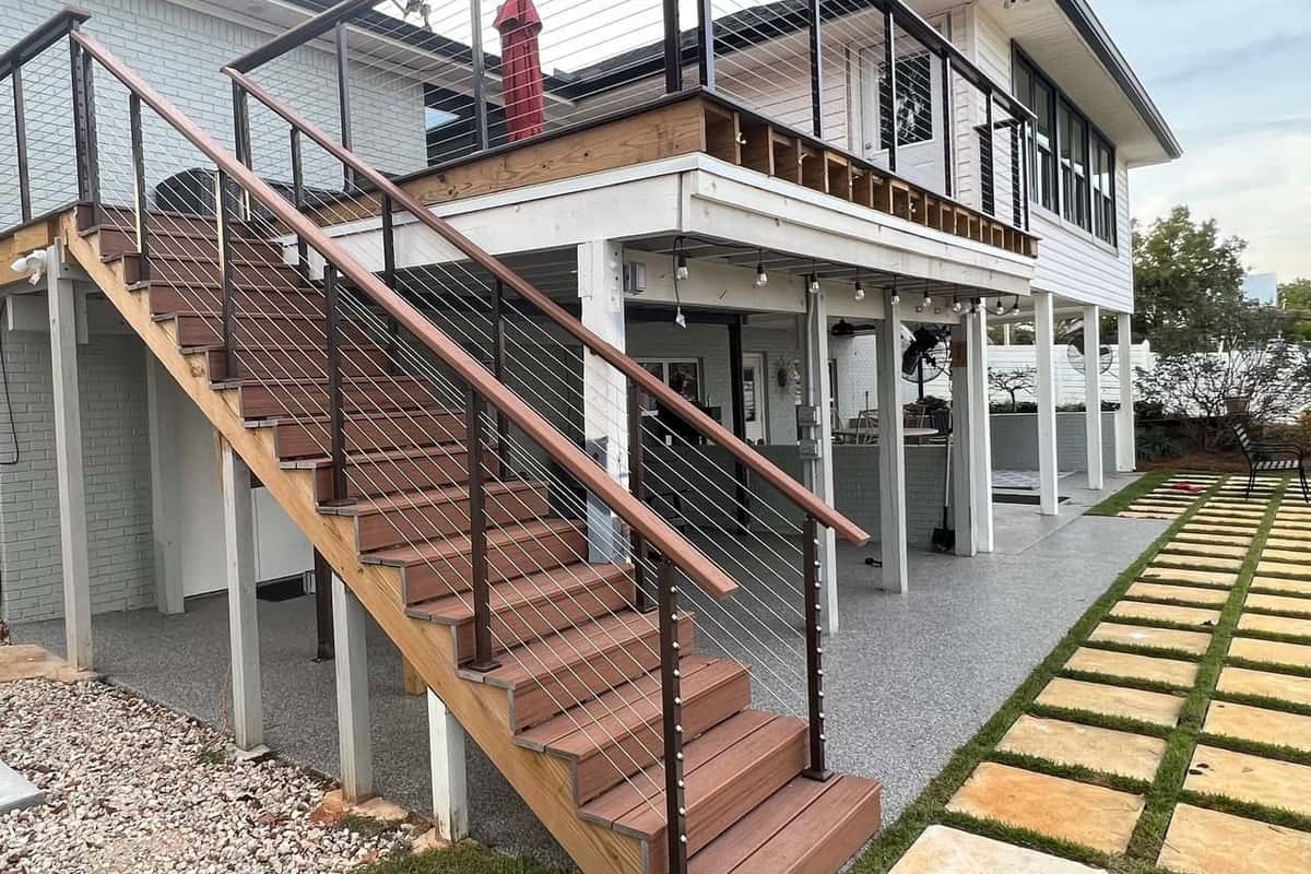 Stained deck stairs and cable-rail balcony on a two-storey house
