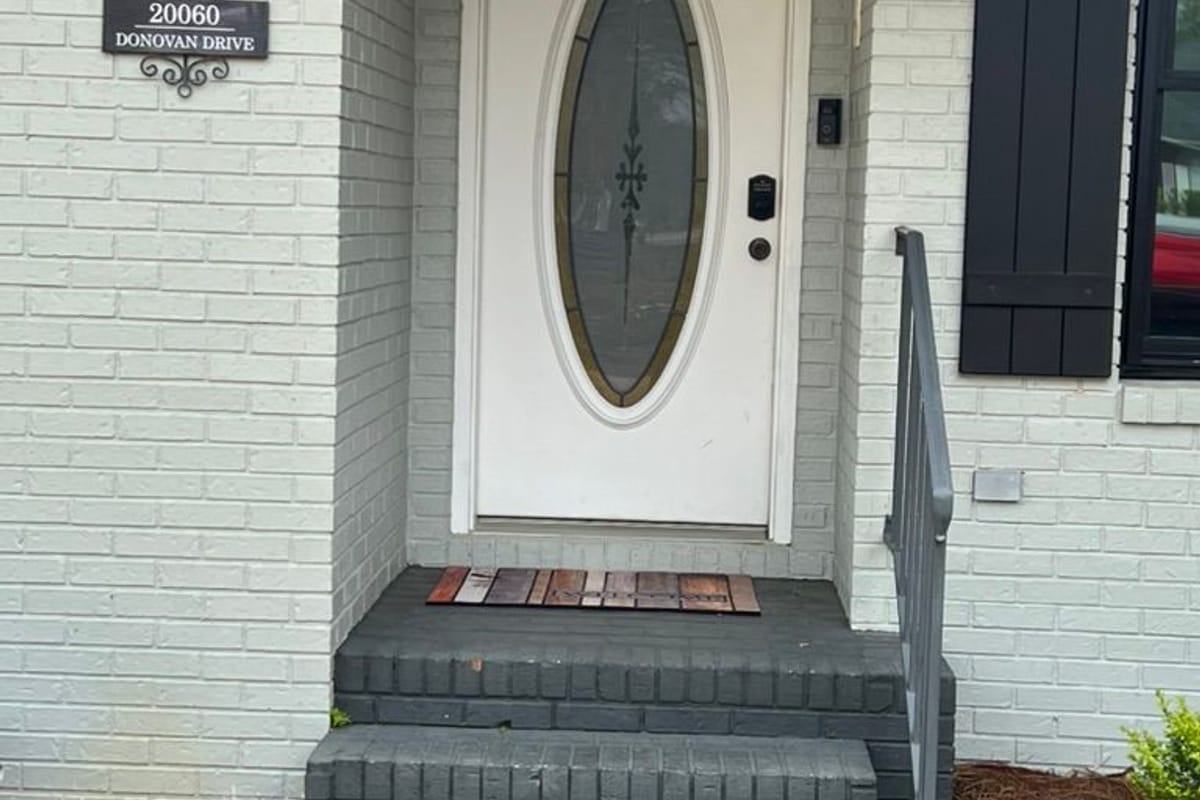 Front entry with a white-painted brick wall, navy board-and-batten shutters and an oval glass door