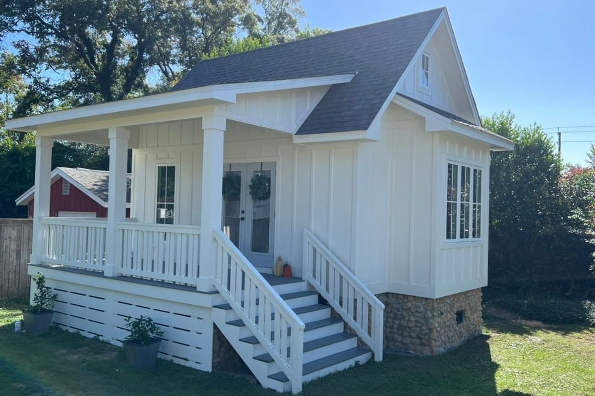 Small white board-and-batten cottage with a new grey roof and a painted front porch