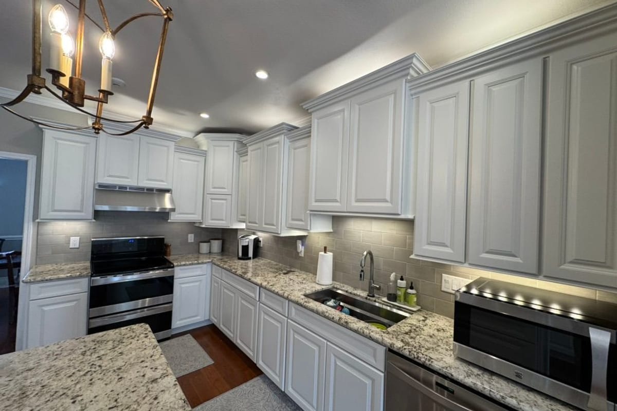 Kitchen with light grey painted cabinets, white trim and a brass pendant over the island