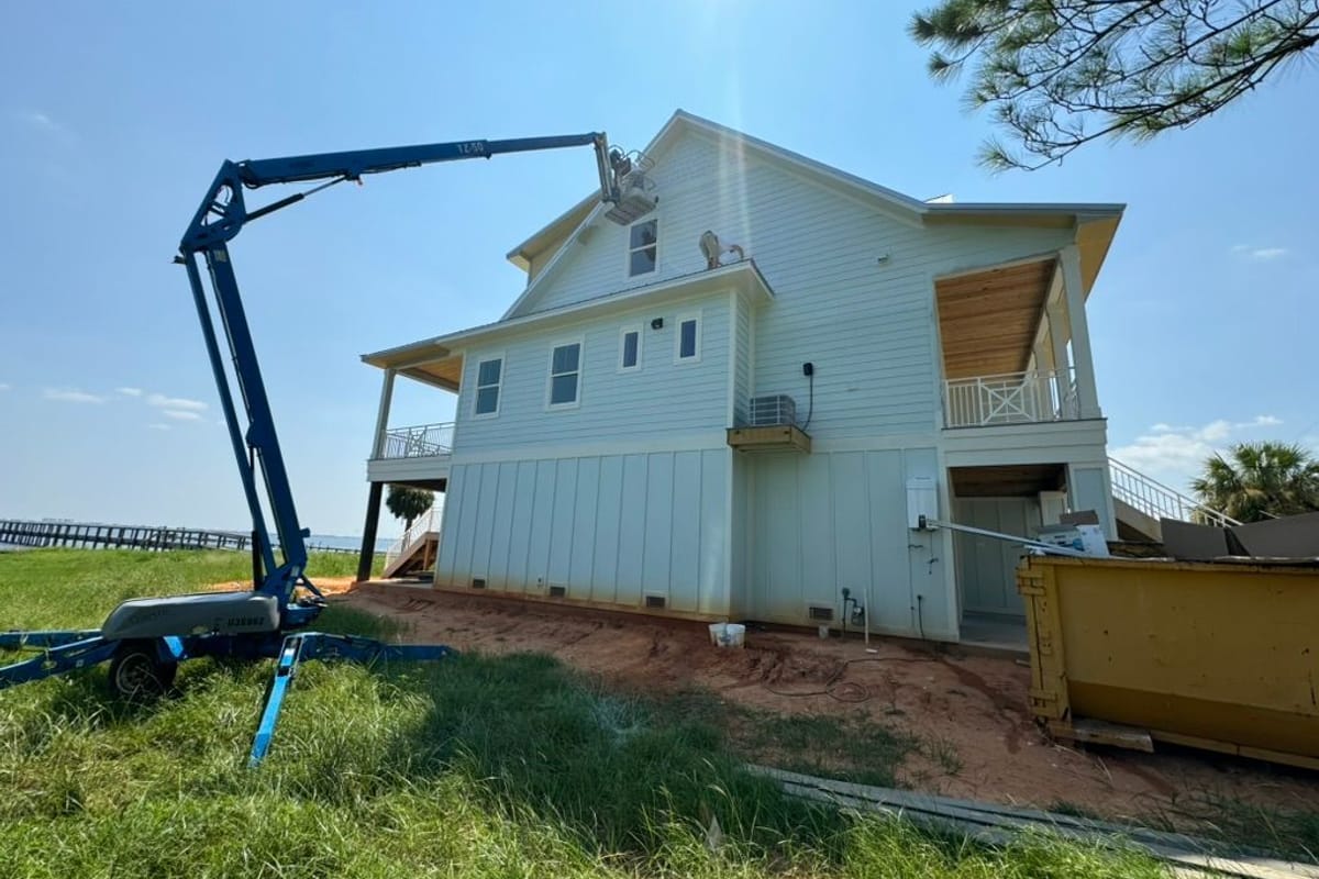 Boom lift set up beside a two-storey house during an exterior repaint