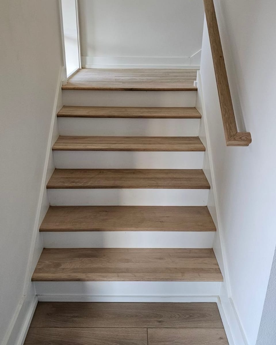 Staircase with freshly painted white risers and stringers against stained wood treads
