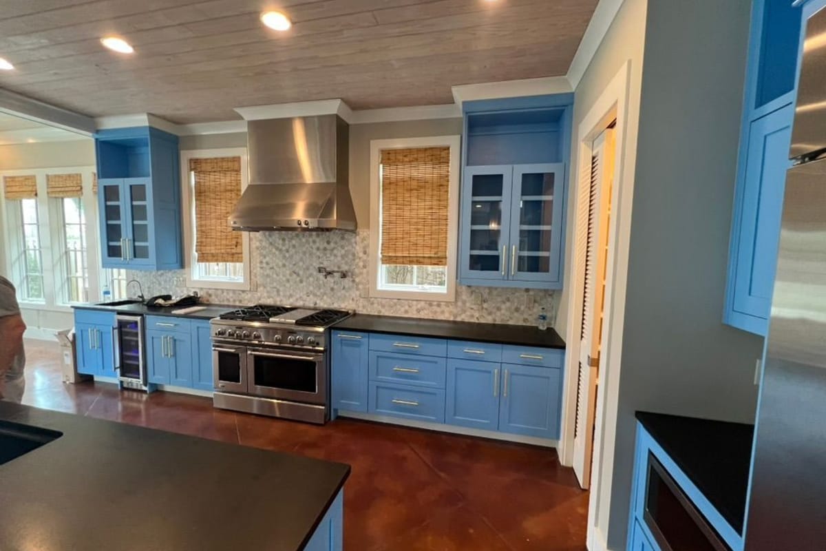 Kitchen with cabinets painted powder blue, a stainless range hood and a wood-plank ceiling