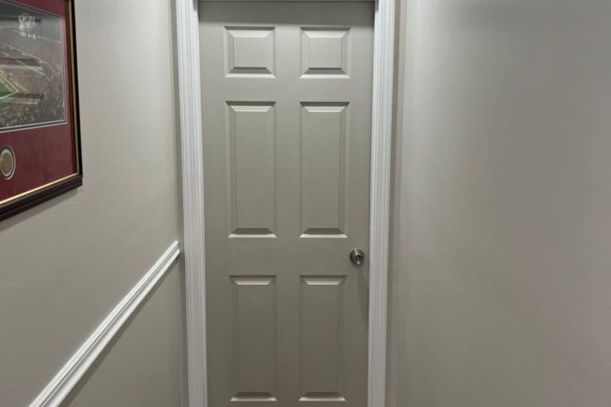 Hallway with crisp white trim, chair rail and doors against light grey walls