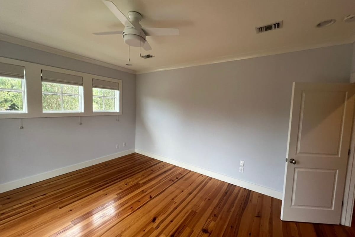 Freshly painted room in warm white with refinished hardwood floors and new window trim