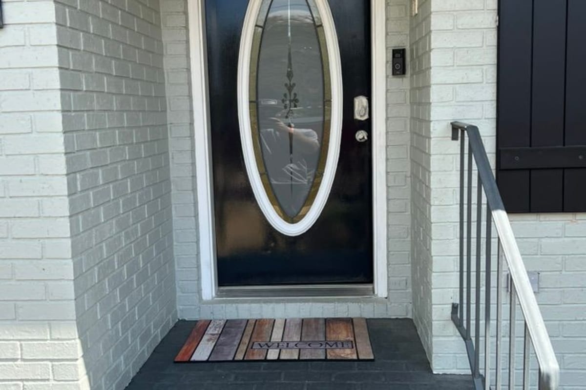Painted front entry with black board-and-batten shutters and a black door on white brick