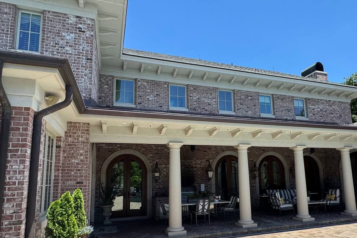 Brick house with white-painted porch columns and arches along a covered patio